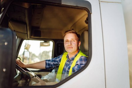 Schöner Fahrer am Steuer eines Lastwagens bei der Arbeit. Fahrer oder Spediteur auf LKW und Anhänger, auf einem Umschlagplatz. Transport-Service.