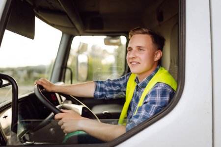 Schöner Fahrer am Steuer eines Lastwagens bei der Arbeit. Fahrer oder Spediteur auf LKW und Anhänger, auf einem Umschlagplatz. Transport-Service.
