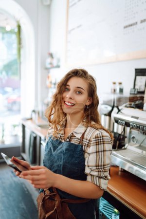 Porträt einer freundlichen Kellnerin bei der Arbeit. Lächelnde Barista hinter einer Theke. Geschäftskonzept, Essen und Trinken