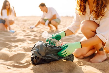 Basura en la playa. Scavengery. Un voluntario recoge botellas de plástico en la orilla del océano. El concepto de conservación ambiental.