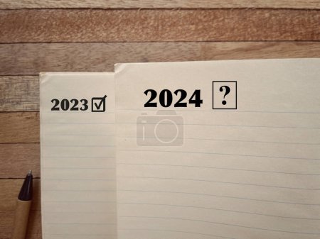 Téléchargez les photos : Concept de motivation du Nouvel An. 2023 et 2024 écrits sur une page de livre. Avec un fond de style flou. - en image libre de droit