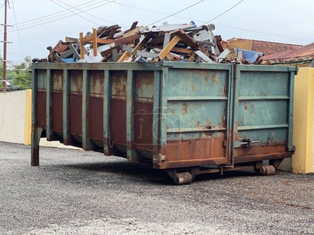 Ein Kipper voller Müll und Materialien in der Nähe eines Gebäudes.