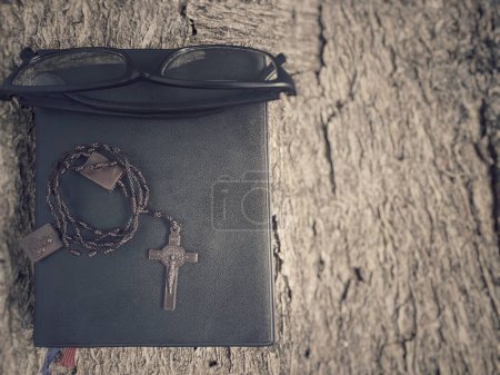 Foto de Collar rosario con biblia y gafas en fondo vintage. Lectura de la Biblia para devoción, reflexión y arrepentimiento. - Imagen libre de derechos