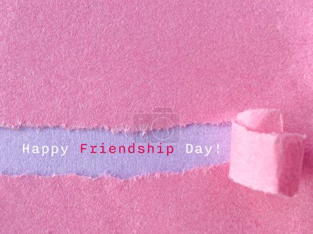 Celebration Happy friendship day text on torn paper background. Stock photo.