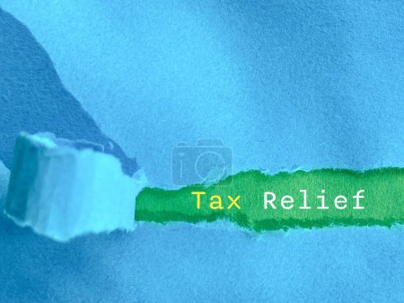 Tax relief text behind torn paper background. Business finance concept.