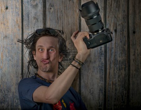 Téléchargez les photos : Homme avec caméra plein cadre noire et lentille grand angle près du vieux mur en bois - en image libre de droit