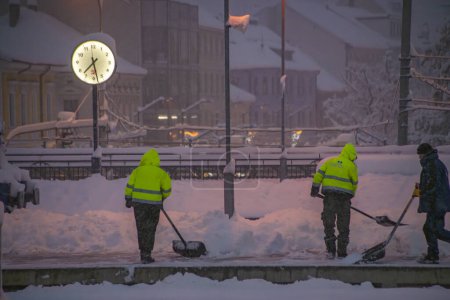 Téléchargez les photos : Ouvriers avec pelle dans un matin d'hiver froid et neigeux à Ceske Budejovice station CZ 02 12 2023 - en image libre de droit