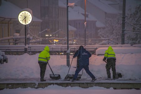 Téléchargez les photos : Ouvriers avec pelle dans un matin d'hiver froid et neigeux à Ceske Budejovice station CZ 02 12 2023 - en image libre de droit