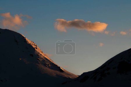 Sonniger, verschneiter Abend auf dem Simplonpass mit blauem Himmel und orangefarbenem Sonnenlicht