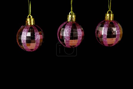 Boules de Noël roses avec des paillettes sur fond noir rosé. Plan studio