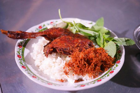 Foto de Pato frito con una pizca de serundeng y albahaca de Madura, Indonesia. Fotografía de alimentos. - Imagen libre de derechos