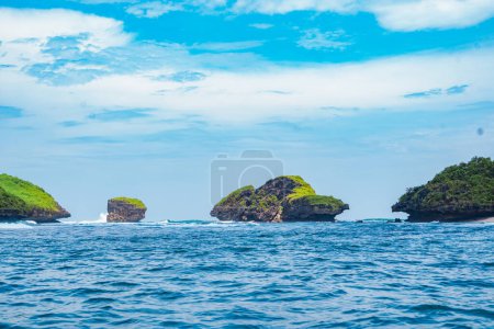 Téléchargez les photos : Formation rocheuse sur l'océan près du Tanjung Kasap ou Cape Kasap, Pacitan, Indonésie. Tiré d'un bateau en mouvement. Photographie de voyage. - en image libre de droit