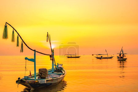 Photo for Moored boats during sunrise with yellow sky in Kenjeran, Surabaya, Indonesia. Long exposure photography. - Royalty Free Image