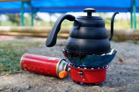 Black Drip kettle on portable stove for camping. Park and outdoor photography.