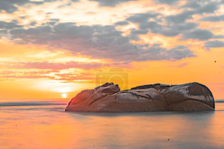 Photo for Dusk on the Tapaktuan beach in Aceh, Indonesia. As the sun begins its descent over Tapaktuan Beach in Aceh, Indonesia, a mesmerizing spectacle unfolds before your eyes. The tranquil waters of the vast ocean gently lap against the rocky shore, while t - Royalty Free Image