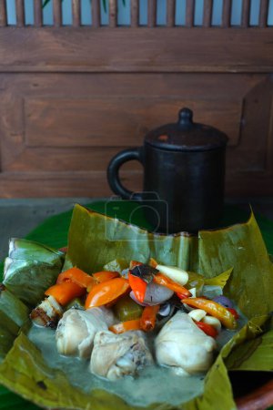 Téléchargez les photos : Garang Asem, la nourriture traditionnelle javanaise est servie sur une assiette d'argile, garnie de feuilles de banane et accompagnée d'un mélange de chili aux yeux d'oiseau, tomates, échalotes, ail, starfruit aigre, et diverses autres épices. Nourriture populaire en Indonésie. - en image libre de droit