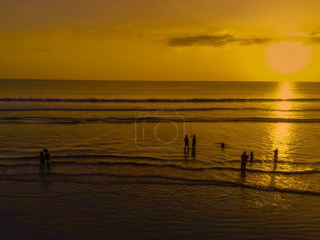 Téléchargez les photos : L'atmosphère crépusculaire à Legian Beach, Bali. Silhouettes de personnes appréciant le coucher de soleil tout en jouant sur la plage. Photographie Nature et Paysage. - en image libre de droit