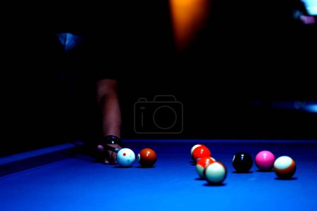 Photo for The hand holding the billiard cue, ready to make a precise strike on the billiard ball on the billiard table in a game of billiards. Sport and game photography. - Royalty Free Image