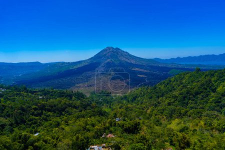 Foto de Monte Batur, un volcán activo en Kintamani, Bali, Indonesia. El volcán está rodeado de árboles y niebla, y hay un lago en primer plano - Imagen libre de derechos