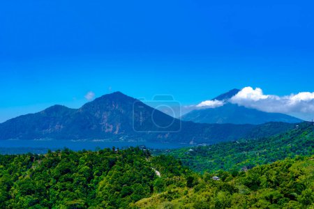 Foto de Monte Batur, un volcán activo en Kintamani, Bali, Indonesia. El volcán está rodeado de árboles y niebla, y hay un lago en primer plano - Imagen libre de derechos