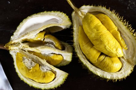 Foto de Una foto de cerca de un Musang King durian, una fruta puntiaguda, de forma ovalada con un fuerte olor. El durian se abre, revelando su pulpa cremosa y amarilla. - Imagen libre de derechos