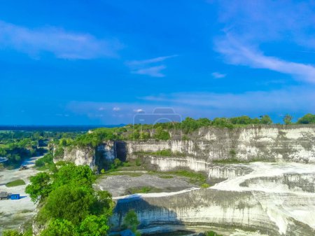 Die majestätischen weißen Kalksteinklippen von Bukit Kapur Jaddih in Bangkalan, Madura, Indonesien, mit der grünen Vegetation und dem blauen Himmel.