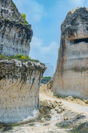 Una foto panorámica del paisaje de la carretera a través de imponentes formaciones rocosas de piedra caliza blanca en Jeddih Hills, Bangkalan, Madura, Indonesia.