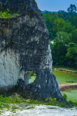 A scenic landscape photo of road through towering white Limestone rock formations at Jeddih Hills, Bangkalan, Madura, Indonesia.