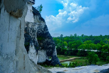 A scenic landscape photo of road through towering white Limestone rock formations at Jeddih Hills, Bangkalan, Madura, Indonesia.