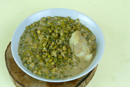 Nahaufnahme von Bubur Kacang Ijo oder Mungobohnenbrei mit Durianstücken auf einer weißen Schüssel. Ein traditionelles indonesisches Gericht aus Mungbohnen, Kokosmilch und Gewürzen