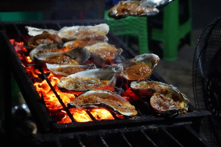 Grilled oyster at Jakarta Food Streets Vendor. Sizzling on a grill, plump oysters offering a taste of the sea with every bite.