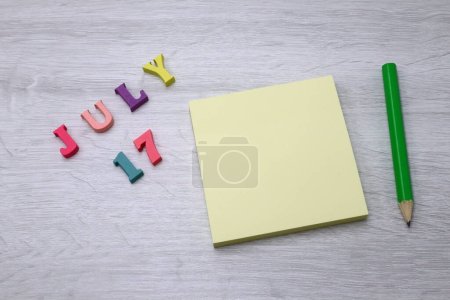 17 de julio - Calendario diario colorido con notas en bloque y lápiz sobre fondo de tabla de madera, espacio vacío para su texto o diseño 