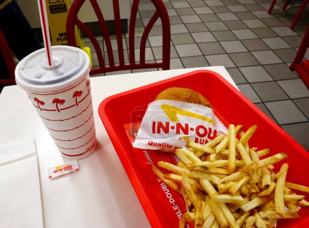 Foto de Los Angeles, California - 6 de octubre de 2019: IN-N-OUT Hamburguesa - Hamburguesa y papas fritas en una bandeja sobre la mesa dentro del restaurante de comida rápida - Imagen libre de derechos