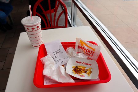 Foto de Glendale, California, Estados Unidos - 19 de mayo de 2023: IN-N-OUT Hamburguesa - Hamburguesa y papas fritas después de comer en una bandeja sobre la mesa dentro del restaurante de comida rápida - Imagen libre de derechos