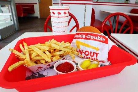 Téléchargez les photos : Los Angeles, Californie - 5 mai 2024 : IN-N-OUT Double Double Burger et frites après avoir fini de manger dans un plateau sur la table à l'intérieur du fast-food - en image libre de droit