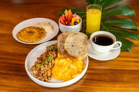 Foto de Desayuno colombiano con arepas, café, pan, huevos, arroz caliente y fruta - Imagen libre de derechos