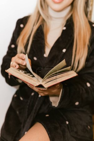 Tag des Buches, 23. April. Blonde Frau mit Brille, die in ihrer Bibliothek ein Buch liest. Gelassenheit.