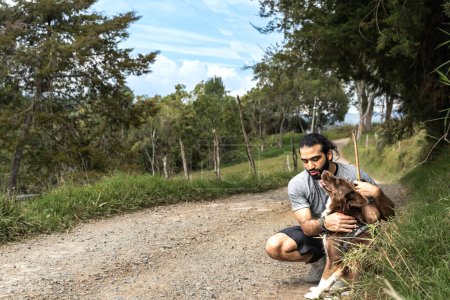 Téléchargez les photos : Adulte mâle mestizo caresser et câliner sa frontière collie chien après l'exercice et le chien lui donnant un baiser - en image libre de droit