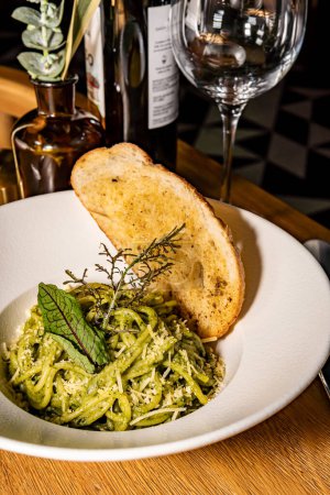 Green pasta with parmesan cheese and spiced bread. Pesto and spinach. Gourmet hotel restaurant.