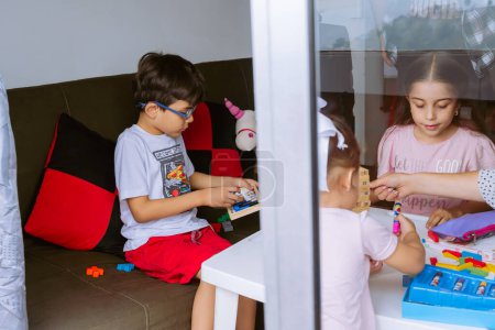 Día Internacional del Niño. Hermosos niños latinos jugando con bloques en una mesa blanca. Juegos lúdicos, divertidos y pensantes. Niños felices en casa.