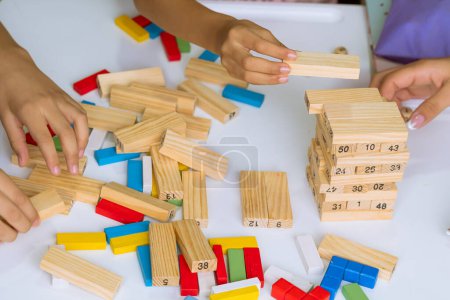 Día Internacional del Niño. Hermosos niños latinos jugando con bloques en una mesa blanca. Juegos lúdicos, divertidos y pensantes. Niños felices en casa.