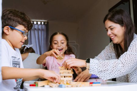 Internationaler Kindertag. Schöne Latino-Kinder, die mit Blöcken auf einem weißen Tisch spielen. Spielerische, lustige und Denkspiele. Glückliche Kinder zu Hause.