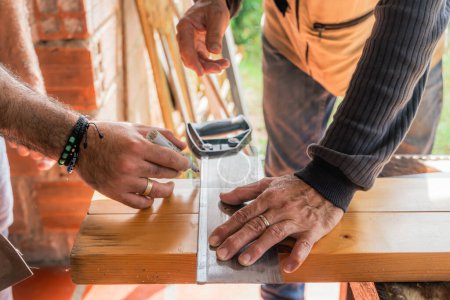 Téléchargez les photos : Des latino-américains qui travaillent avec une scie à main et du bois chez eux. Père et fils dans leur atelier. Outils de menuiserie. - en image libre de droit