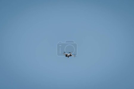 Téléchargez les photos : Drone volant dans le ciel sur fond bleu pour l'espace de copie. - en image libre de droit
