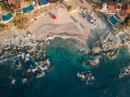 Top down aerial view of Conchas Chinas Beach in Puerto Vallarta Mexico showing rocks, sand, water.