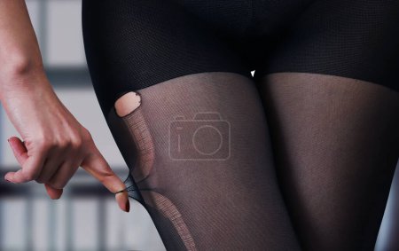 Foto de Cadera sexy de una chica en pantimedias negras rotas sobre un fondo borroso. Detalle del primer plano del cuerpo femenino - Imagen libre de derechos