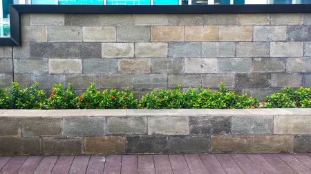 Foto de Una pared de piedra natural, un poco de planta y sala de estar con camino de madera, el hermoso diseño simple de un arquitecto al aire libre moderno parque. - Imagen libre de derechos