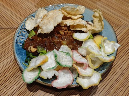 Gado Gado indonésien traditionnel avec sauce aux arachides, croustillant au poisson et vide Melinjo sur table en bois