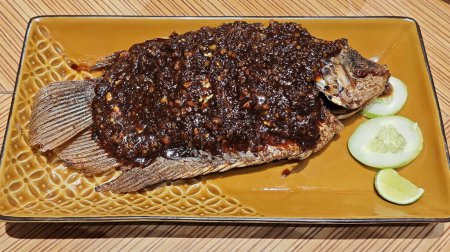 Savory Grilled Gurame Fish with Candlenut Spice on Elegant Golden Plate.