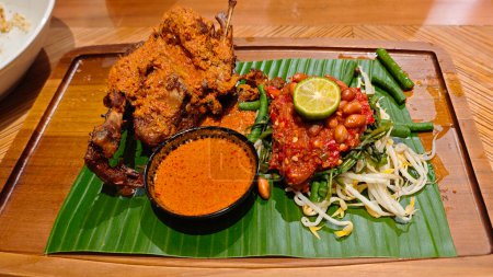 Photo for Traditional Ayam Taliwang indonesian cuisine with Vegetable Mash and Curry Soup on Banana Leaf - Royalty Free Image